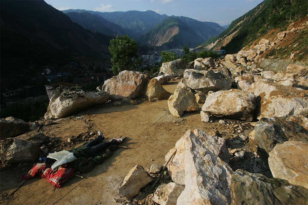 2008年5月14日，綿陽市山路上一名罹難者的屍體被大石塊覆蓋。