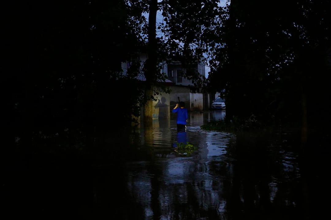  中國武漢，河水缺堤，一名村民在洪水中走路。