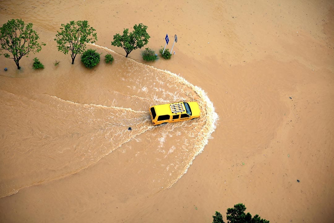 貴州省，一輪汽車在淹水的道路前進。
