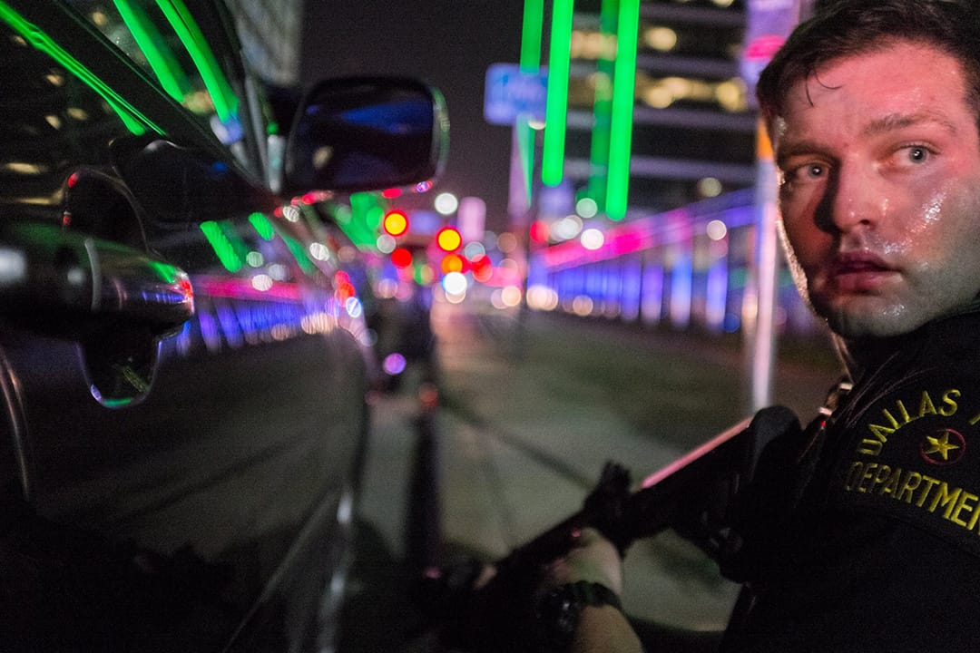 达拉斯反对警察暴力对待黑人游行中有枪手狙击射杀警员，Robert Moore蹲在一个持枪警察背後，与他一同经历惊险时刻。