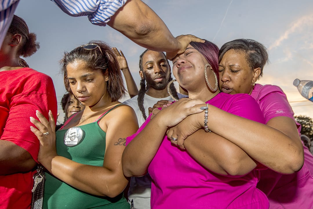 黑人小販斯特林(Alton Sterling)的親友在他被射殺的地方哭泣。