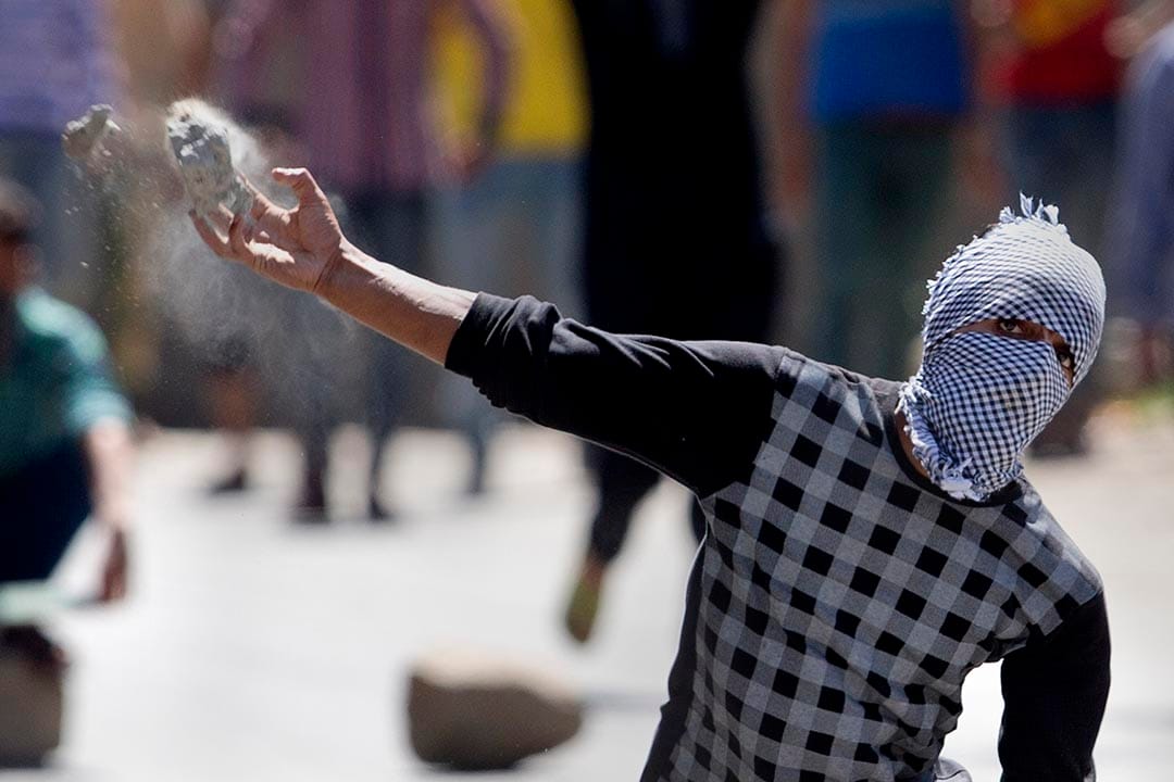 一名蒙面的喀什米尔示威者向警方投掷石头。