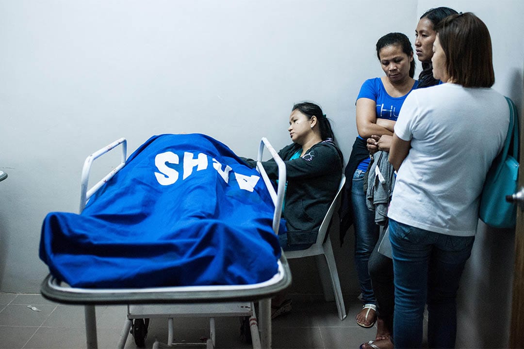 2016年8月20日,菲律宾马尼拉,家属站在一个警员的尸体旁。