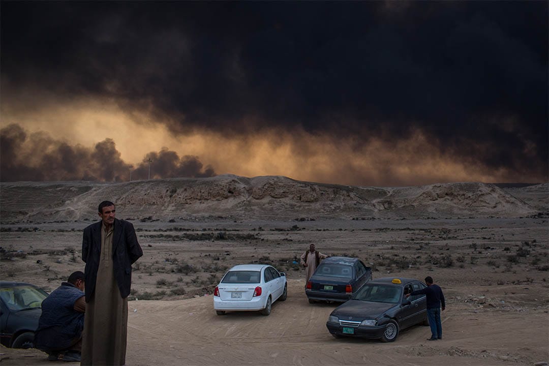 2016年11月9日,伊拉克蓋亞拉,人們站在起火的油井附近。