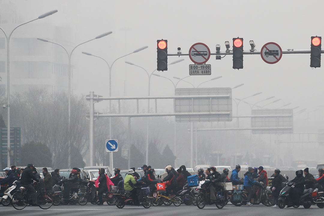 中国北京,市民骑单车和电动车横过马路。
