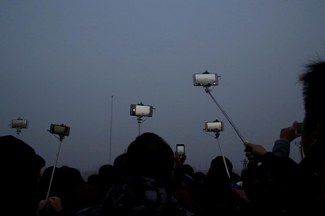 中国北京,市民在雾霾中为天安门广场的升𣄃仪式拍照留念。