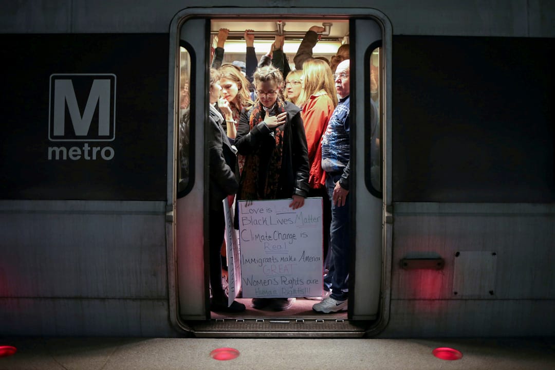 在美国华盛顿,拿着标语的女士正乘坐地铁前往示威区。