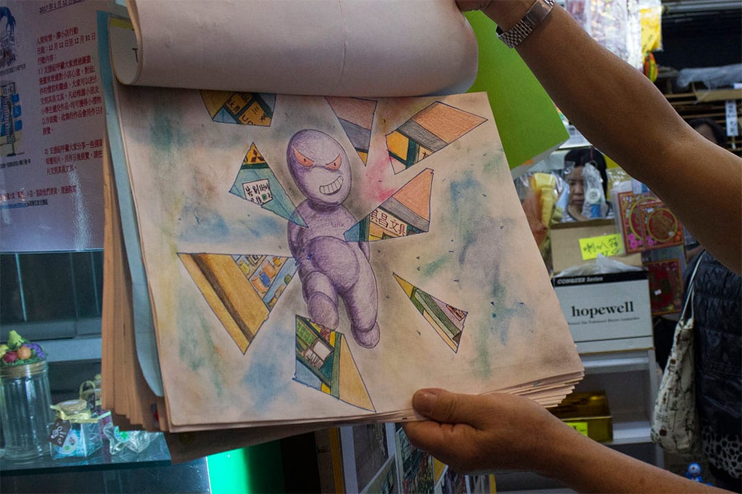  老闆羅先生翻開一張由街坊送贈的畫作，寓意領展破壞小店的生存空間。