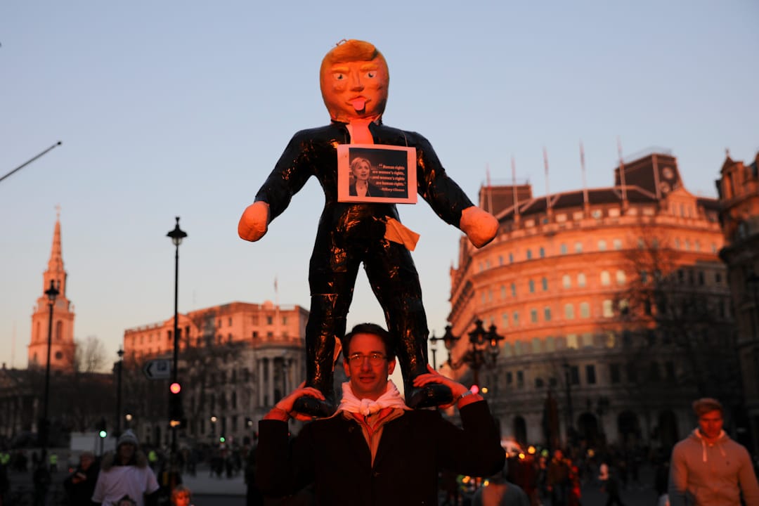 在英国伦敦,一名抗议者手持特朗普总统肖像在街上游走。