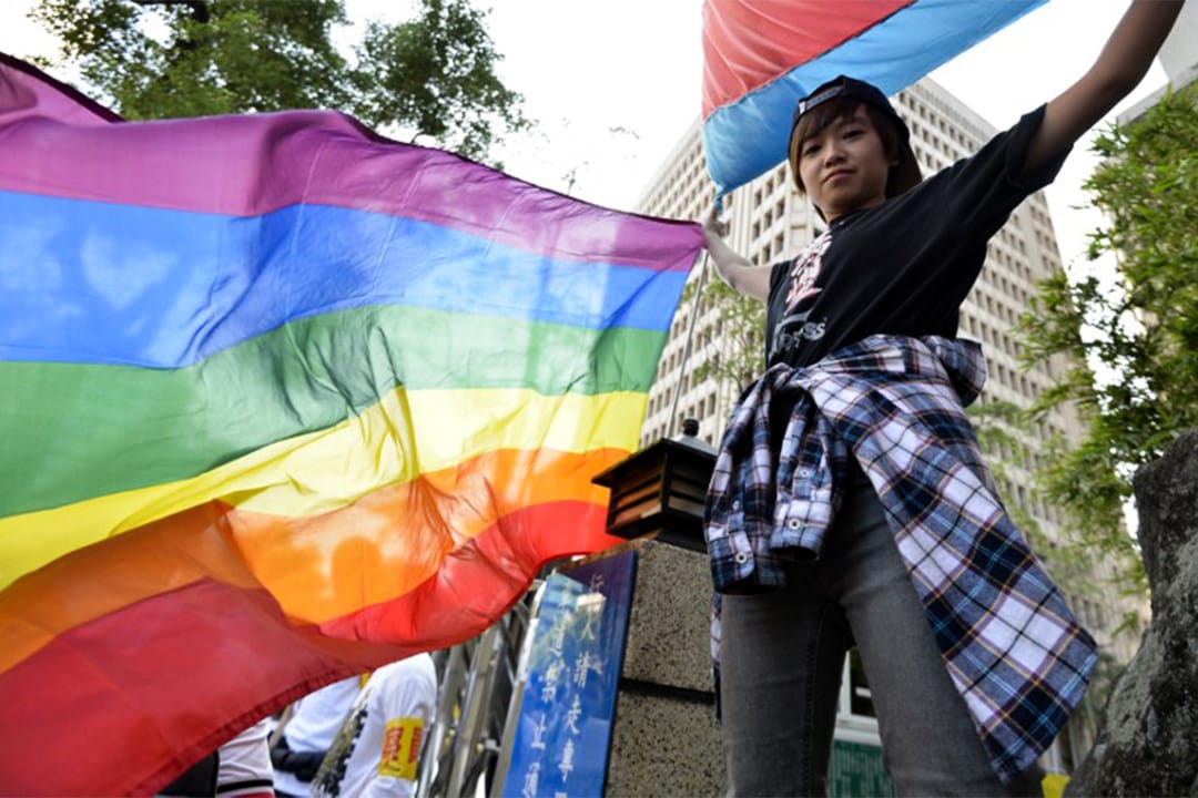 有台灣青年高舉象徵性少數群體(LGBT)的彩虹旗幟。