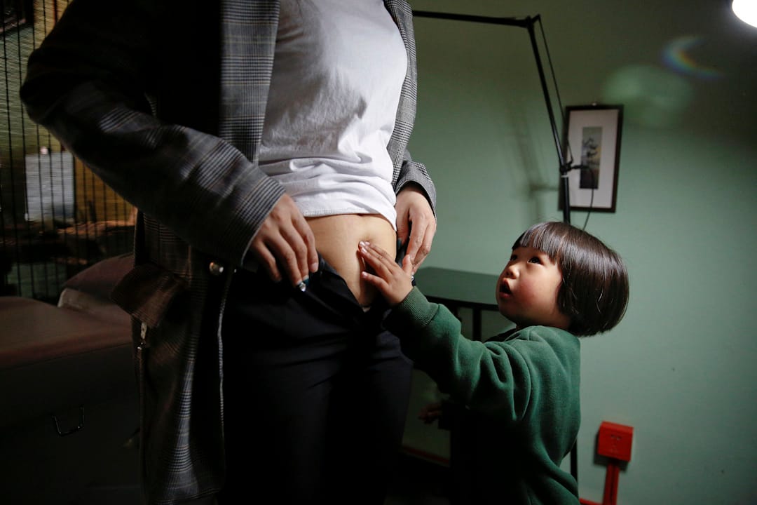 Grace的3歲大女兒摸着媽媽肚皮上的疤痕。