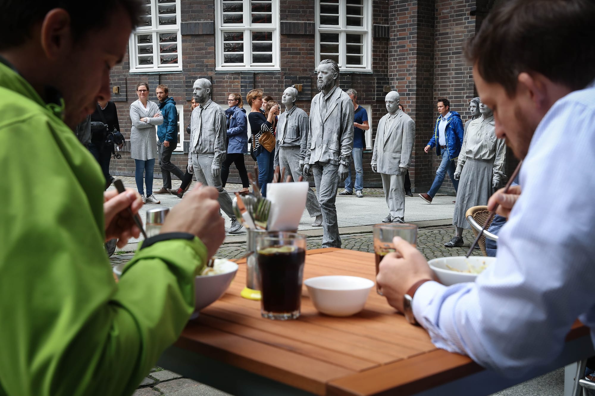 2017年7月5日,「1000 Figures」的參與者,走過漢堡市中心,經過一間戶外餐館。