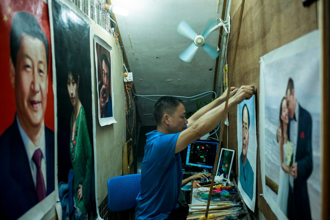 一名大芬村畫家小心翼翼將一幅毛澤東肖像掛在牆上。