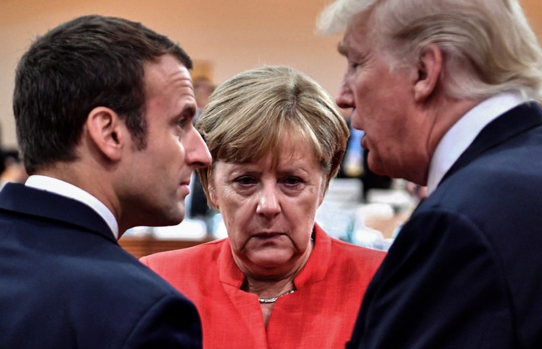 2017年7月7日，在德國漢堡，當地正在舉行二十國集團峰會。法國總統馬克龍、德國總理默克爾和美國總統特朗普在第一次工作會議展開前夕互相寒暄。
