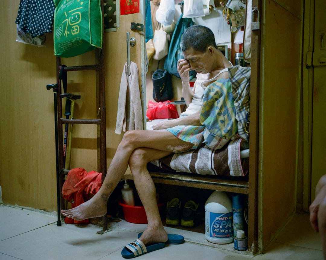 2017年6月，港島區一個板間房，住客坐在床邊看電視。