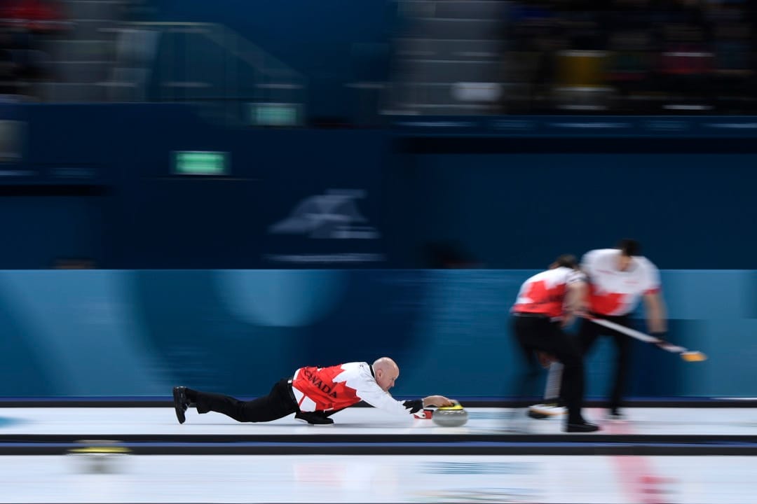 2018年2月21日，在加拿大对丹麦的冰壶比赛循环赛阶段中，加拿大队的 Kevin Koe 把冰壶推向赛道另一端的标靶。