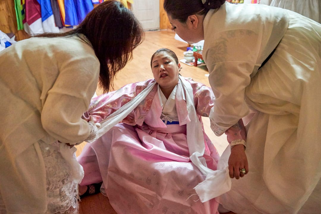 韩国京畿道,几位萨满巫师正在为一名信徒死去的母亲作名为“羊肠”的法事,其用途在于洗涤死者的灵魂和引导死者到来世。教徒相信死者的灵魂能透过巫师的身体在此法事跟信徒对话。