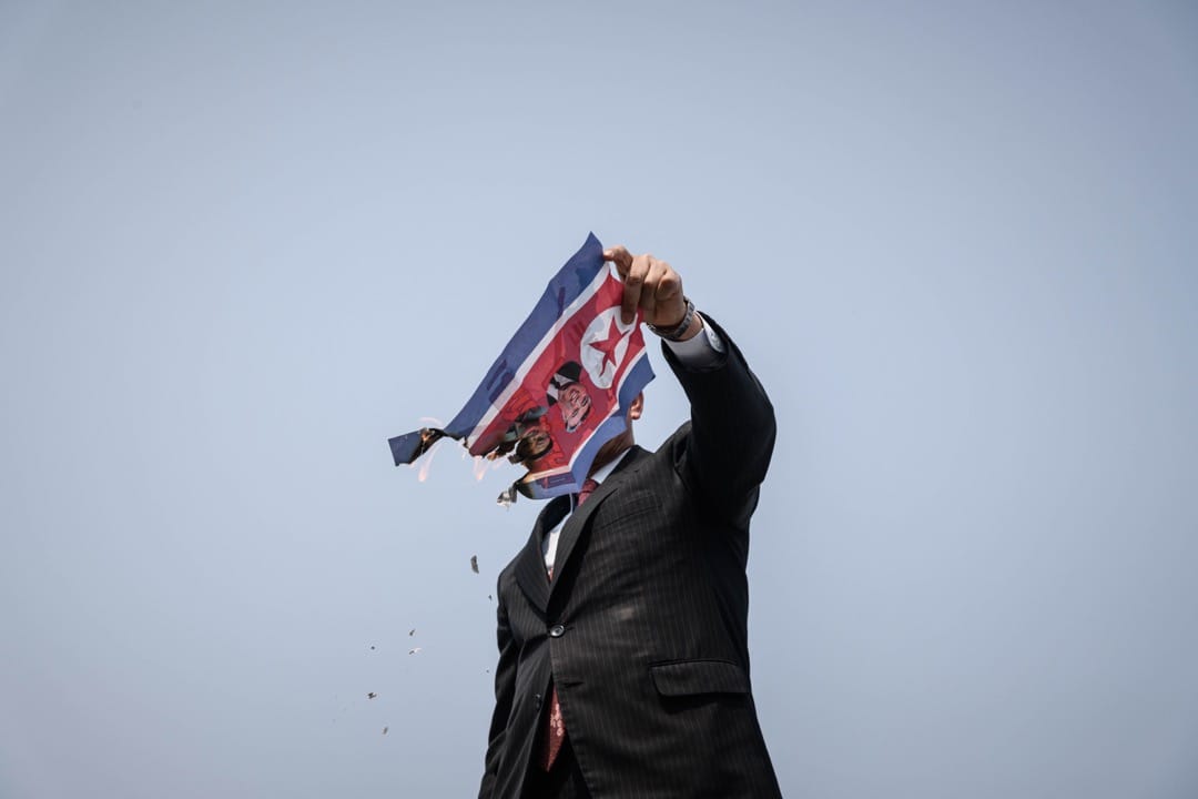 2018年4月27日,南韓坡州臨津閣和平公園通往板門店非軍事區的統一大橋檢查站,一名反北韓示威者在焚燒北韓國旗。