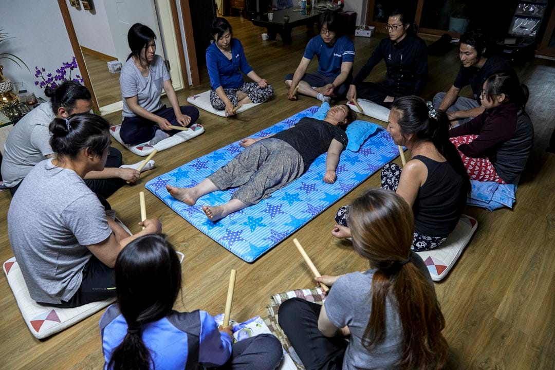 韩国堤川市,萨满巫师Cheonsindangju正和弟子们为一名女子在她的住所驱魔。