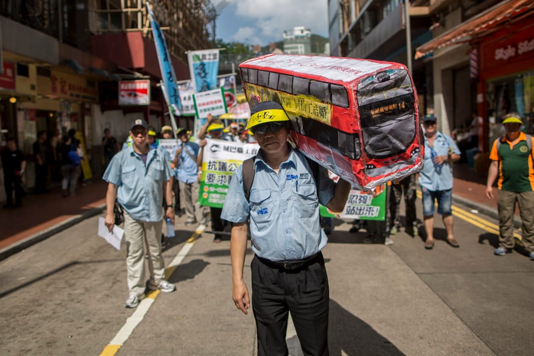 新巴職工會的李先生是一名巴士司機，手捧自製的巴士道具參與五一勞動節遊行。他表示希望公司善待員工，減少工時，避免因疲勞駕駛影響乘客的安全。