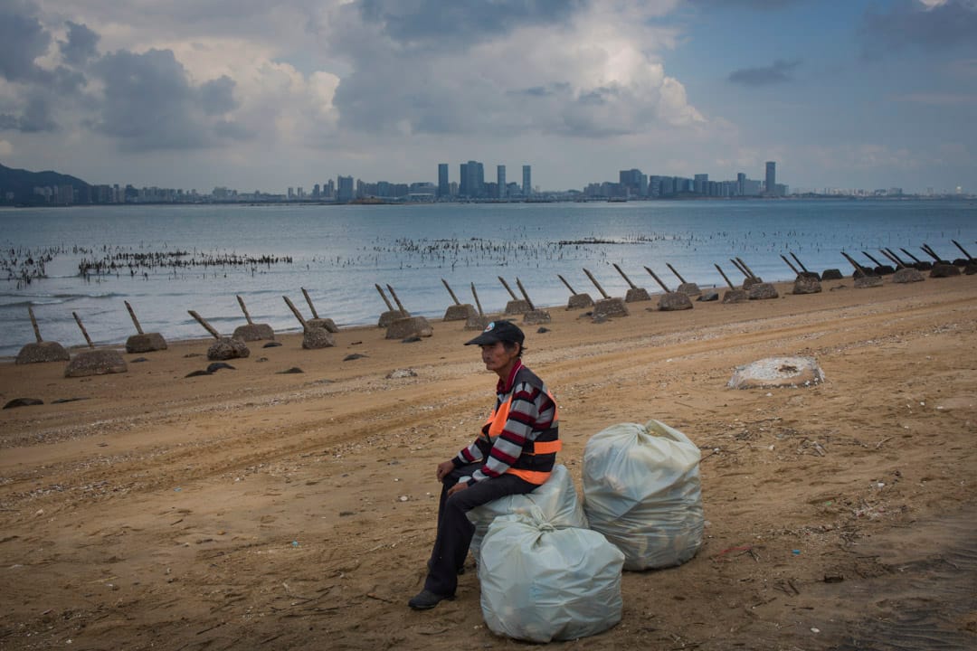 2018年8月20日，小金門海灘上佈滿軌條砦，一名海灘工作人員正在歇息，對岸為中國廈門市。
