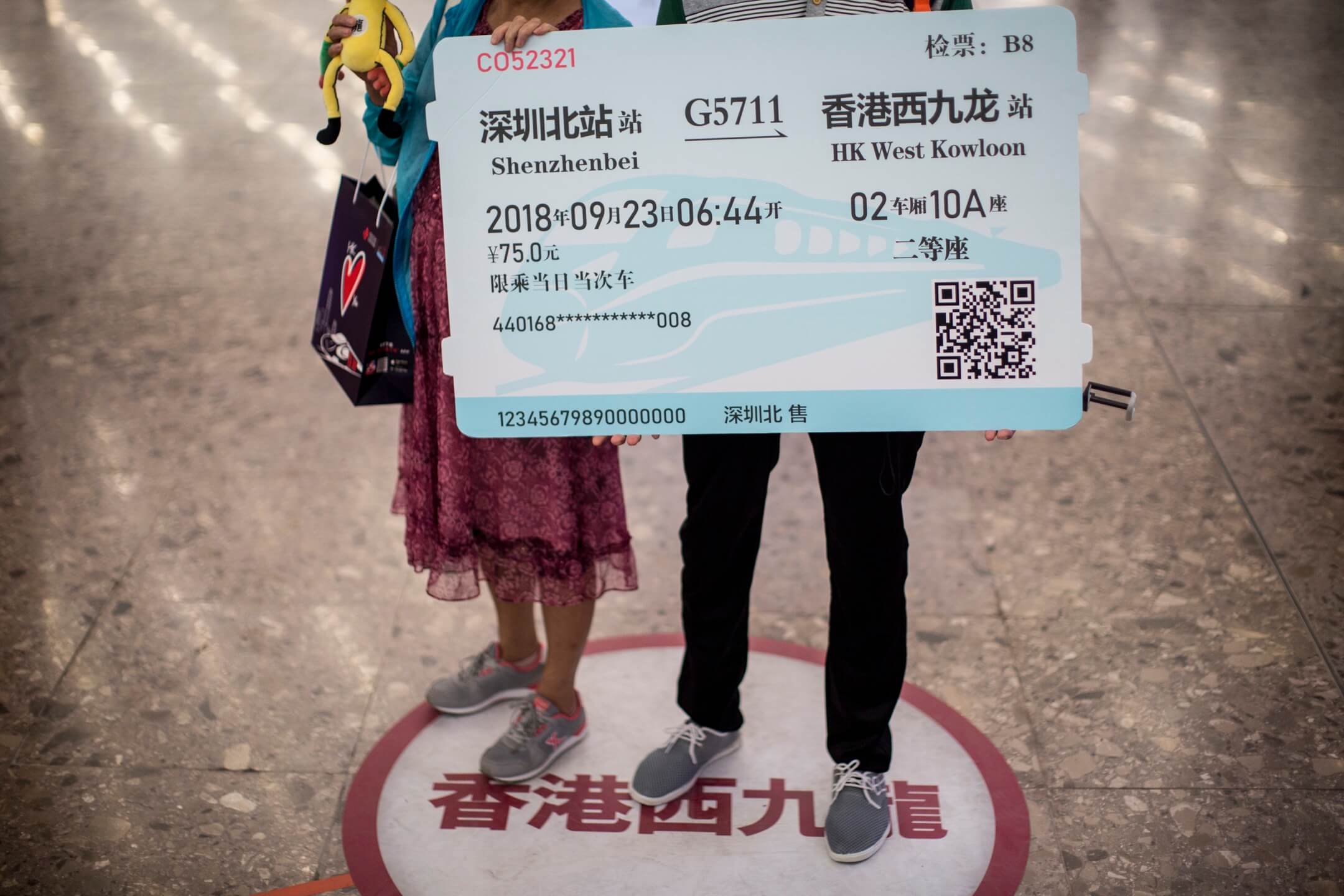 香港西九龙高铁站入境大堂，两名内地旅客拿著道具车票拍照。