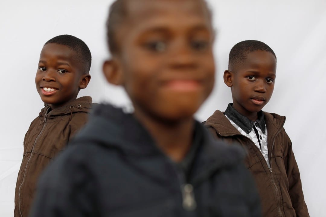 8岁三胞胎兄弟Simphiwe，Syamthende和Sneliswa微笑望向镜头。