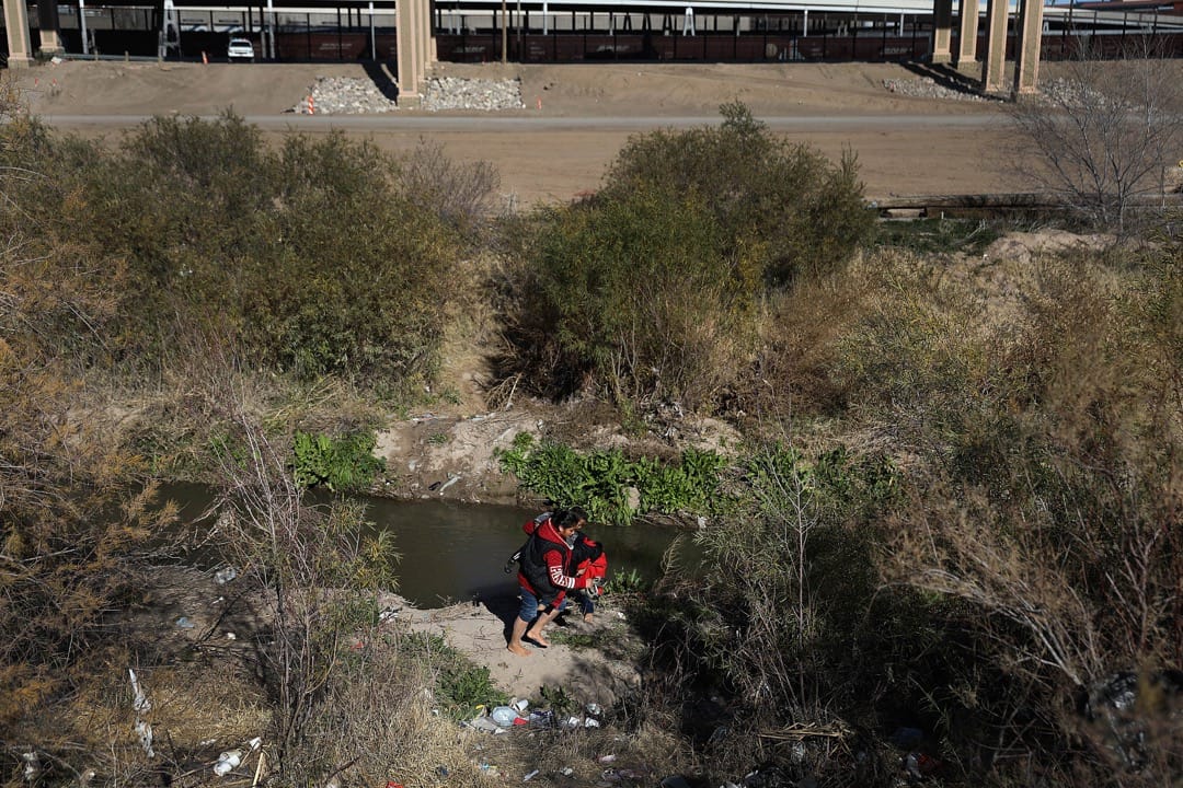 墨西哥邊境城市華雷斯城,一名來自危地馬拉的移民,手抱著孩子預備越過美墨邊境的一段格蘭德河,抵達美國領土後尋求庇護。