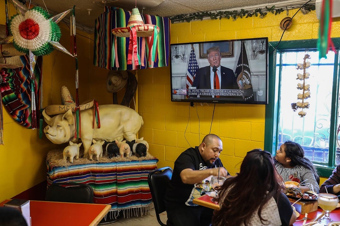美國德州,Carlos Luna與女兒Dareyna Luna及其家庭在埃爾帕索市的一家墨西哥餐廳裏進餐,電視上播放著美國總統特朗普發表講話的片段。