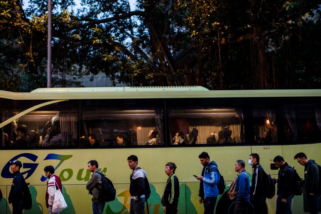 3月1日清晨,工人們如常到裕民坊遊憩公園外,等候來接送他們到地盤工作的旅遊巴士。
