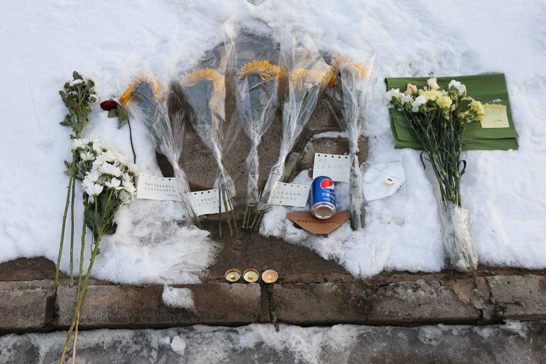 2020年2月8日,北京通惠河畔「送別李文亮」的字跡旁,市民獻上的鮮花。