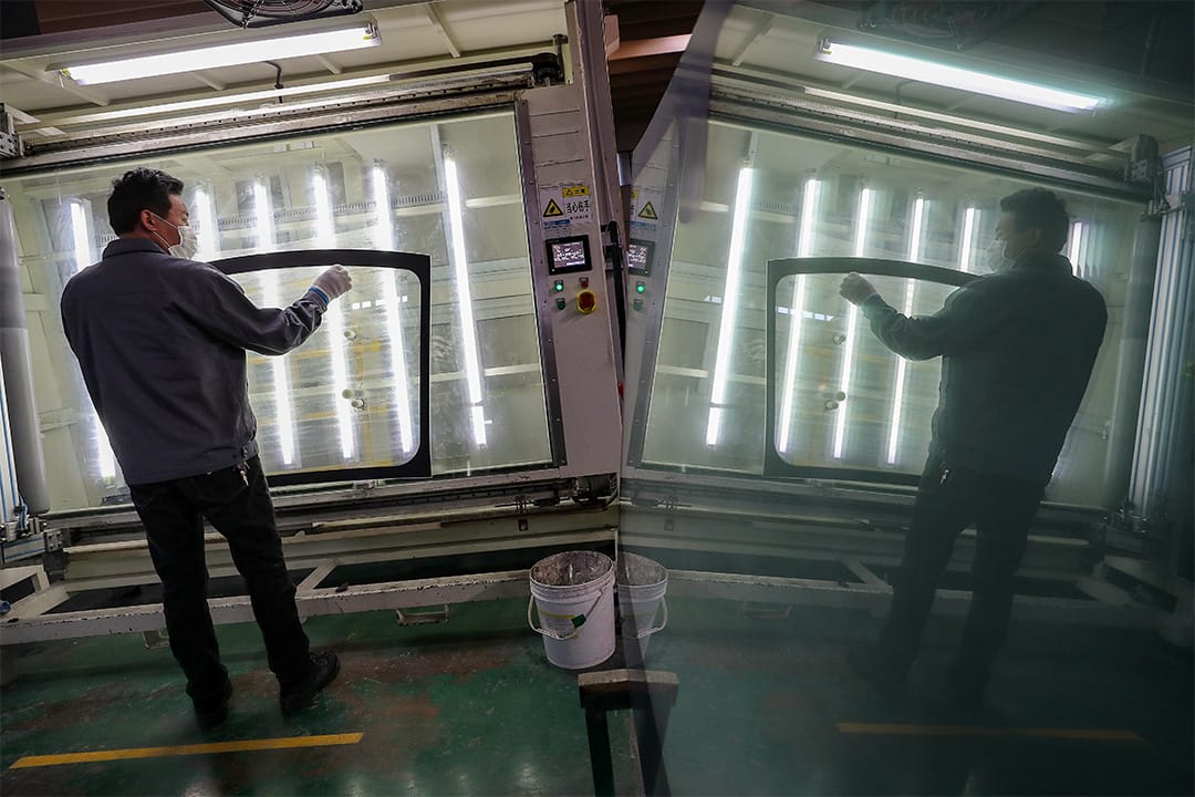 2020年3月4日南通,一名戴口罩的工人在汽车挡风玻璃厂内工作。