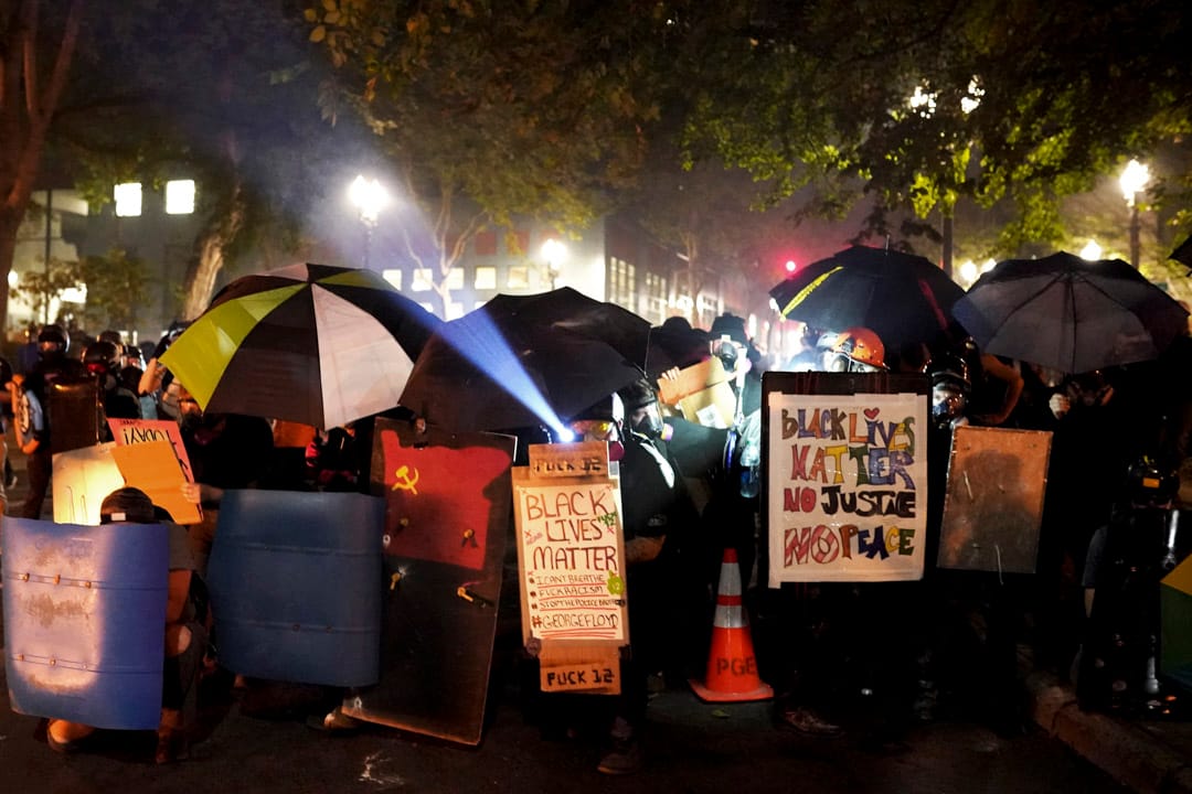 2020年7月21日，波特兰示威者以伞及一些胶板筑起防线，向警方推进。
