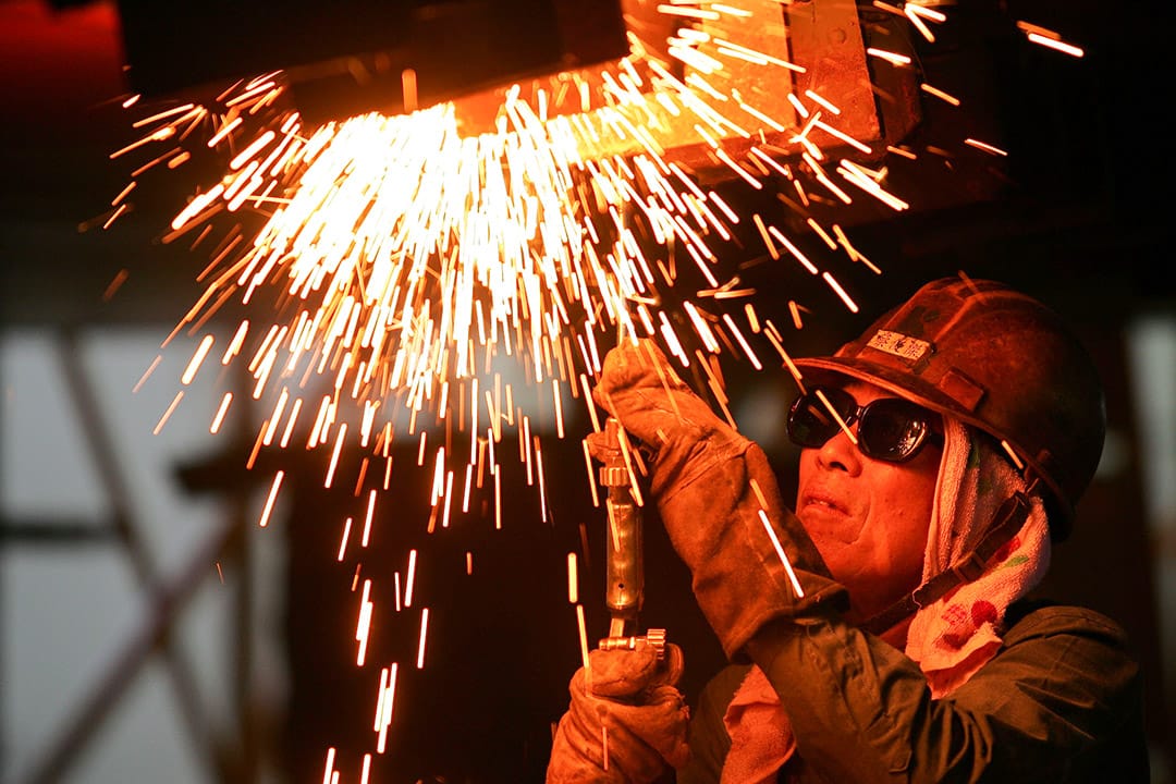 2010年8月16日，一名員工在台灣高雄的船廠焊接一艘船的部件。