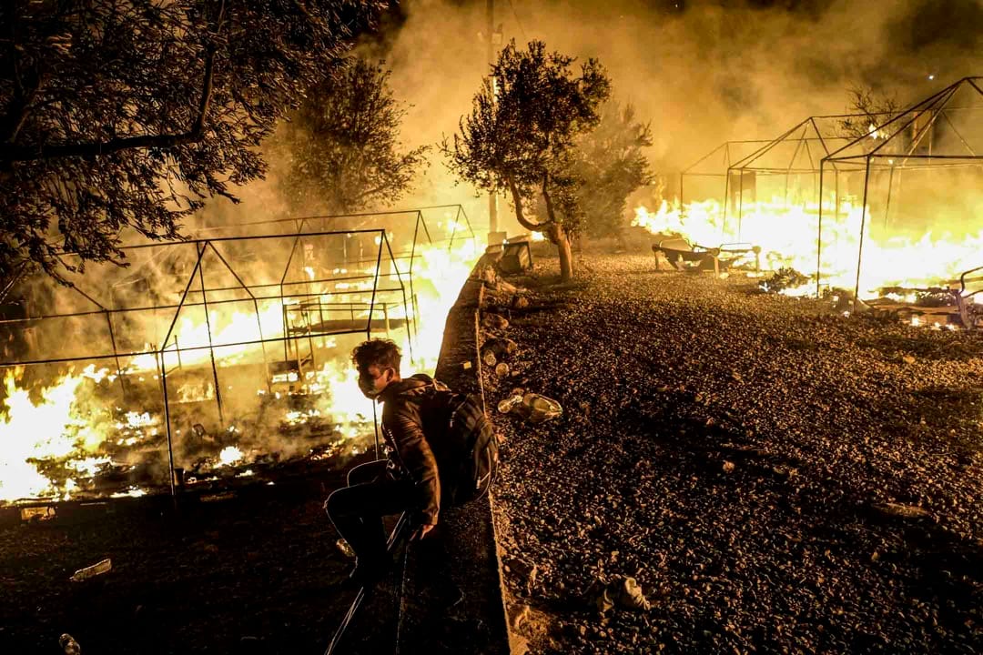 2020年9月9日,希臘萊斯沃斯島、莫里亞難民營發生火災,一名逃到希臘尋求庇護者坐看著營地被燒毀。