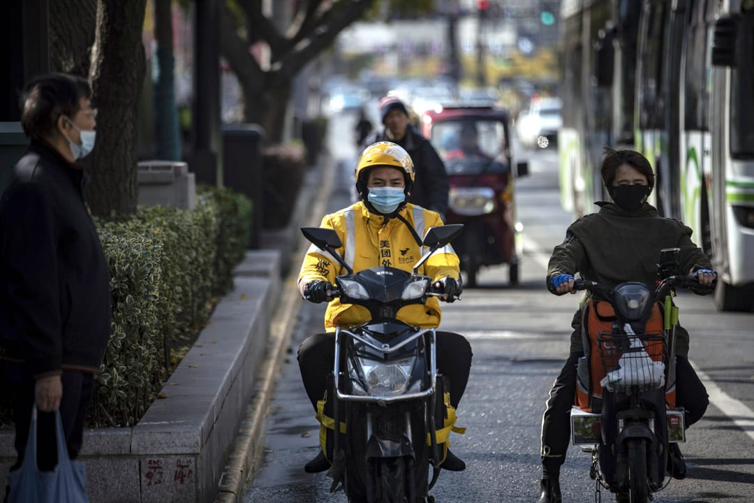 2020年11月29日,美團的送餐快遞員在上海的交通信號燈旁等候。