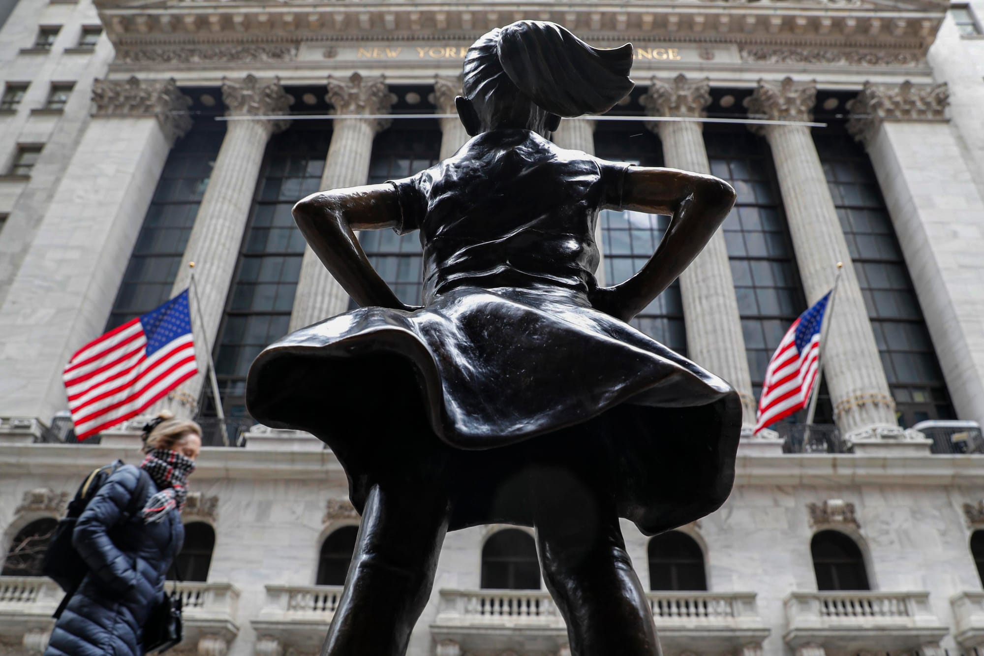 2020年3月12日紐約,一名戴著圍巾的行人在紐約證券交易所 (NYSE) 和無畏女孩雕像旁散步。