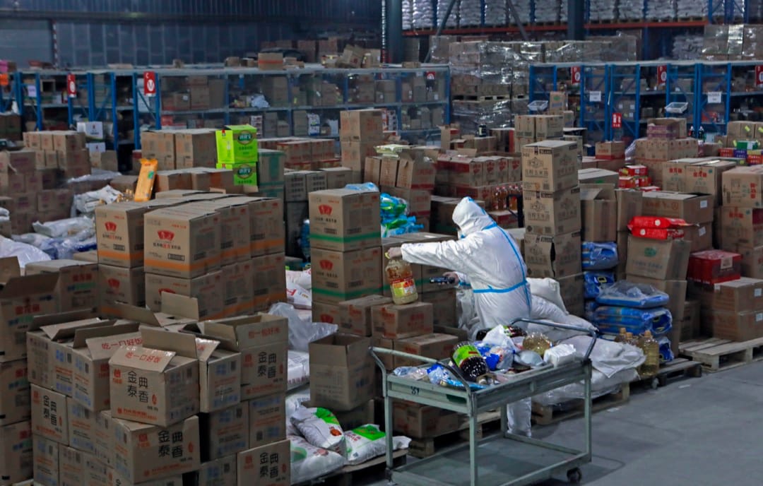 2022年1月10日，中国城市西安，一名穿著保护衣的工作人员在网购公司京东的货仓内整理货物。