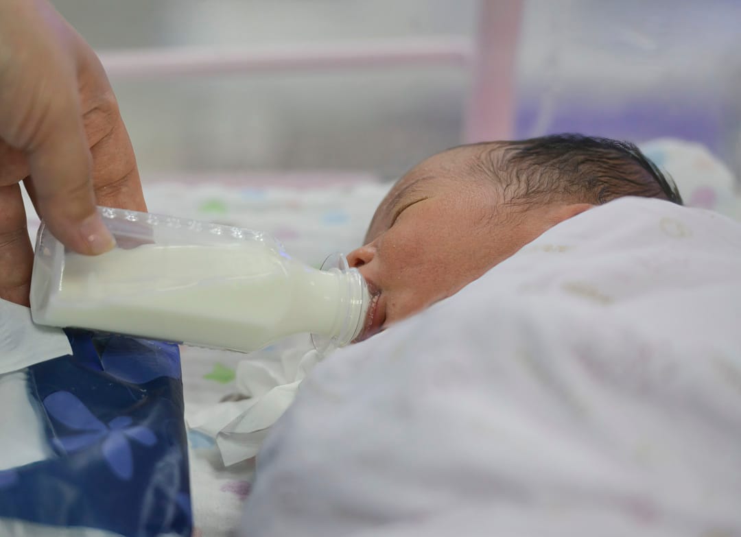 2021年4月25日,中国一间医院新生儿护理中心的病房里,一名新生婴儿正在用奶瓶喂食。