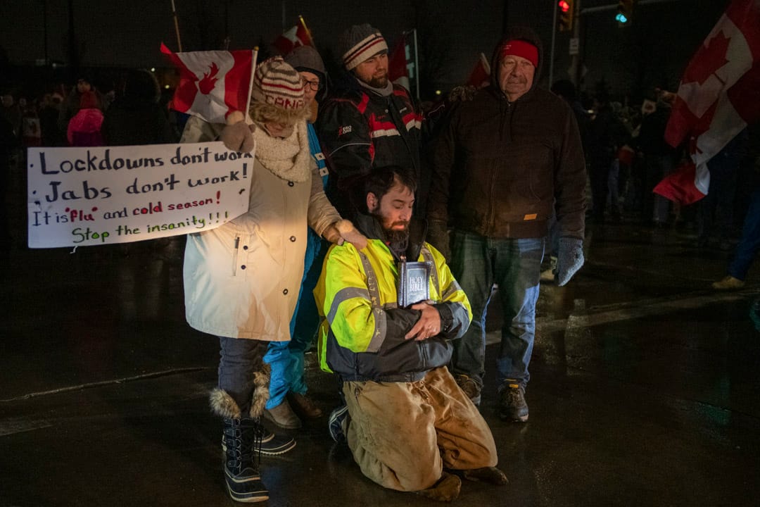 2022年2月11日，加拿大安大略省溫莎市，數名「自由車隊」反疫苗示威的參與者在路中心祈禱，連同其他示威者一起堵塞連接美國的大使橋。