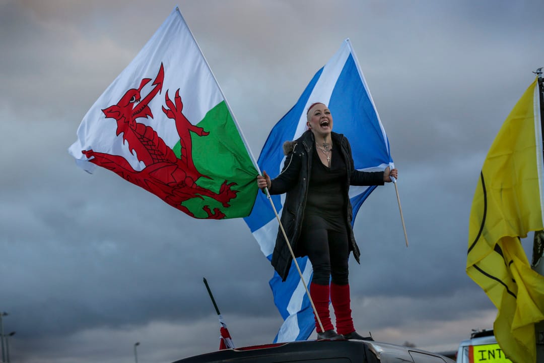 2022年2月6日，英國，首都倫敦市郊小鎮科巴姆，一名反疫苗示威者站在自己的小型貨車上揮動威爾斯和蘇格蘭國旗。