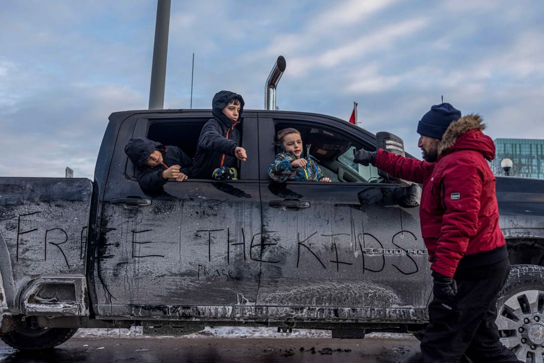 2022年1月30日，加拿大首都渥太華，三名小孩從一輛停泊在路邊的車上向一位反疫苗示威者打招呼。