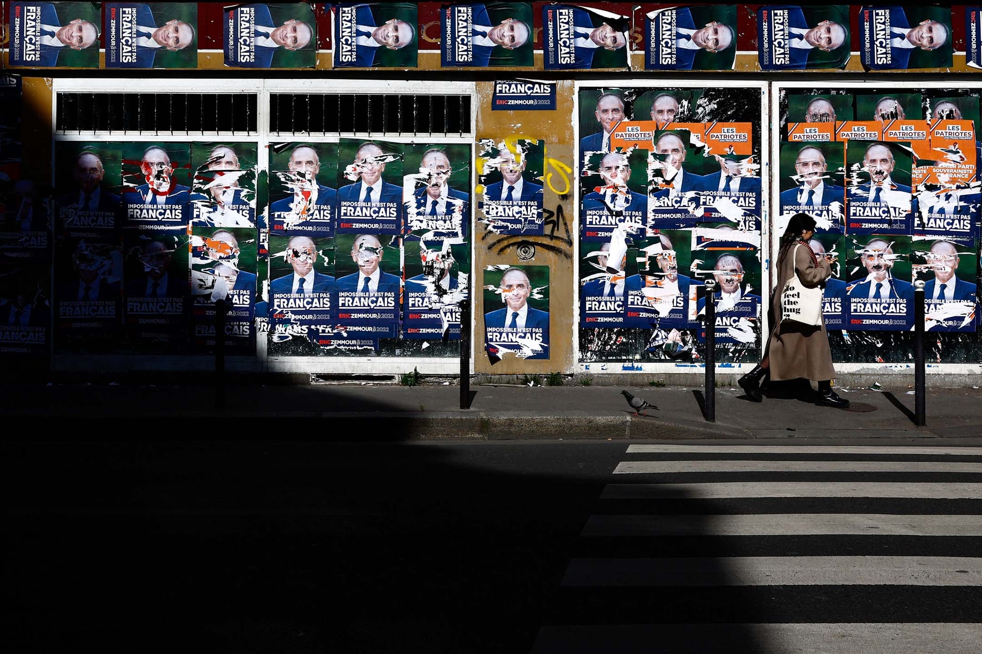 2022年4月4日,一名妇女从一堵被撕毁的法国极右翼评论员泽穆尔(Eric Zemmour)的总统竞选海报旁走过。
