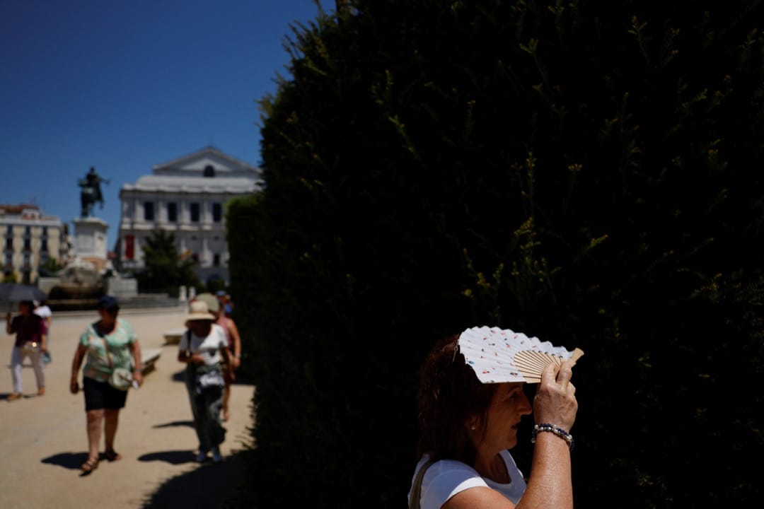 2022年7月10日,西班牙马德里,一名游客用折扇挡太阳。