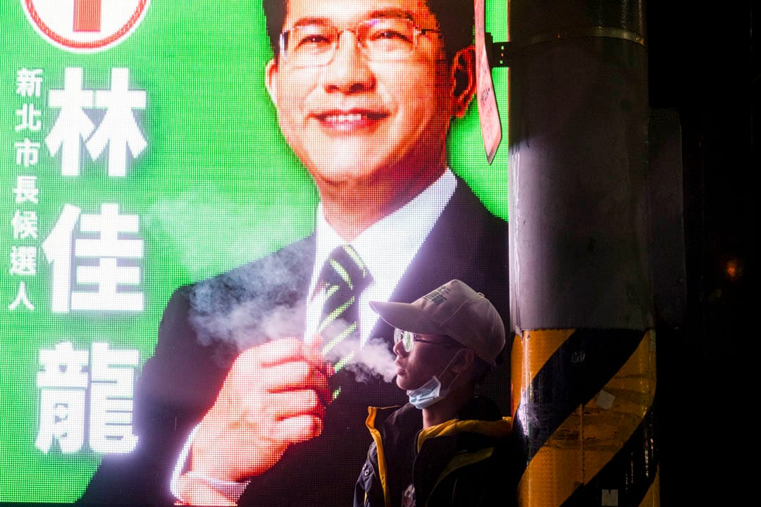 2022年11月24日，民进党新北市市长候选人林佳龙举行造势晚会，一名支持者在旁抽烟。