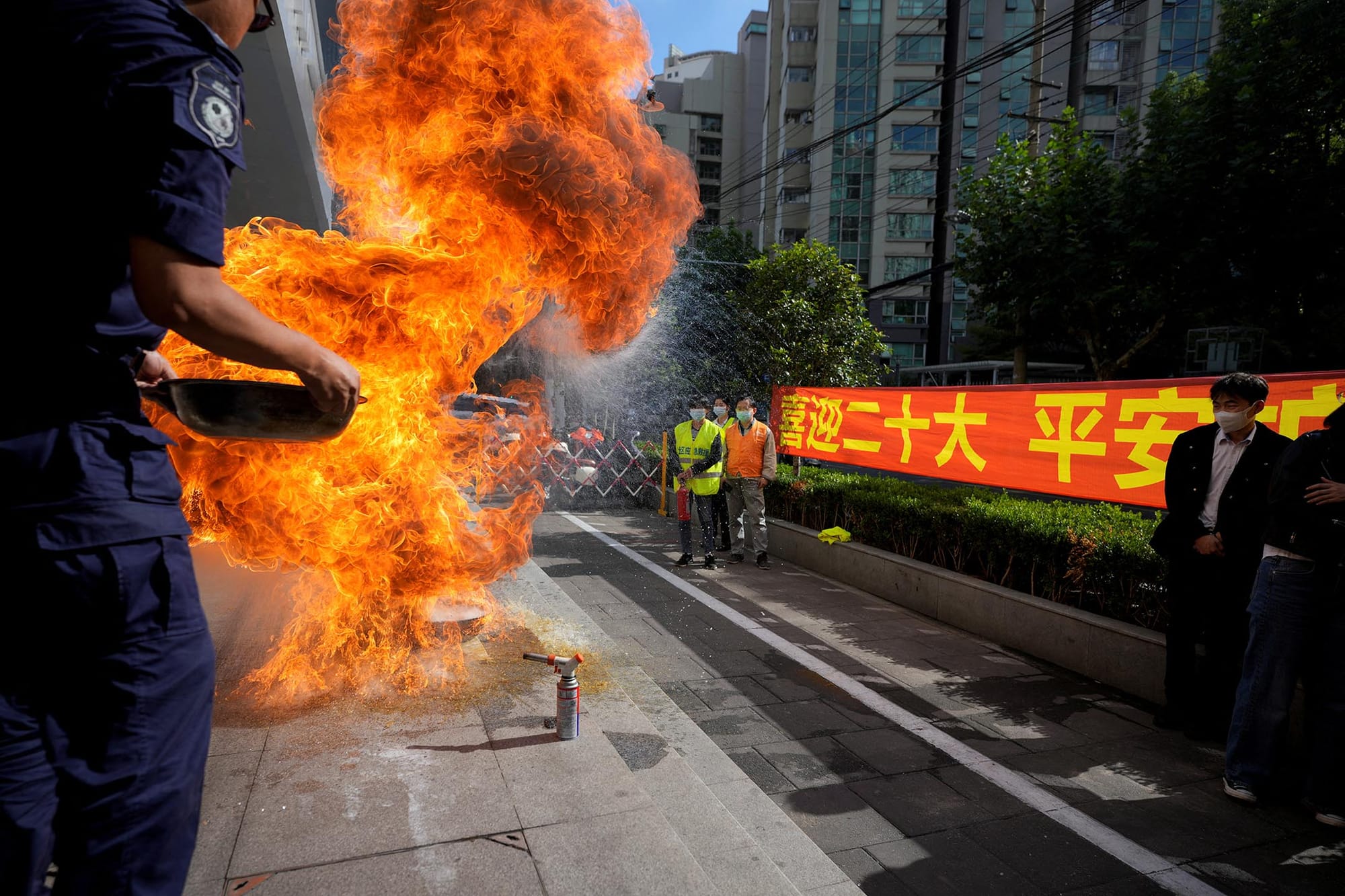 2022年10月13日，中国上海的一个住宅区，人们在中国共产党第二十次全国代表大会的横幅旁参加紧急演习。摄：Aly Song/Reuters/达志影像