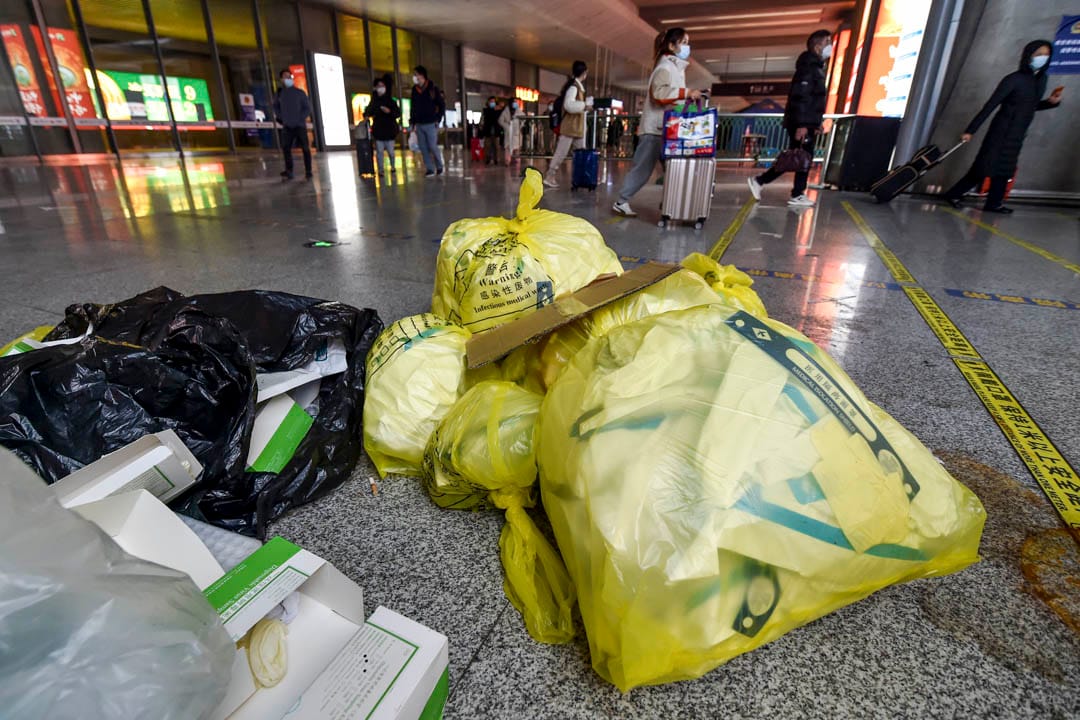 2022年12月7日，中国南京，高铁南京南站内的乘客走过暂放在地上的医疗废料。