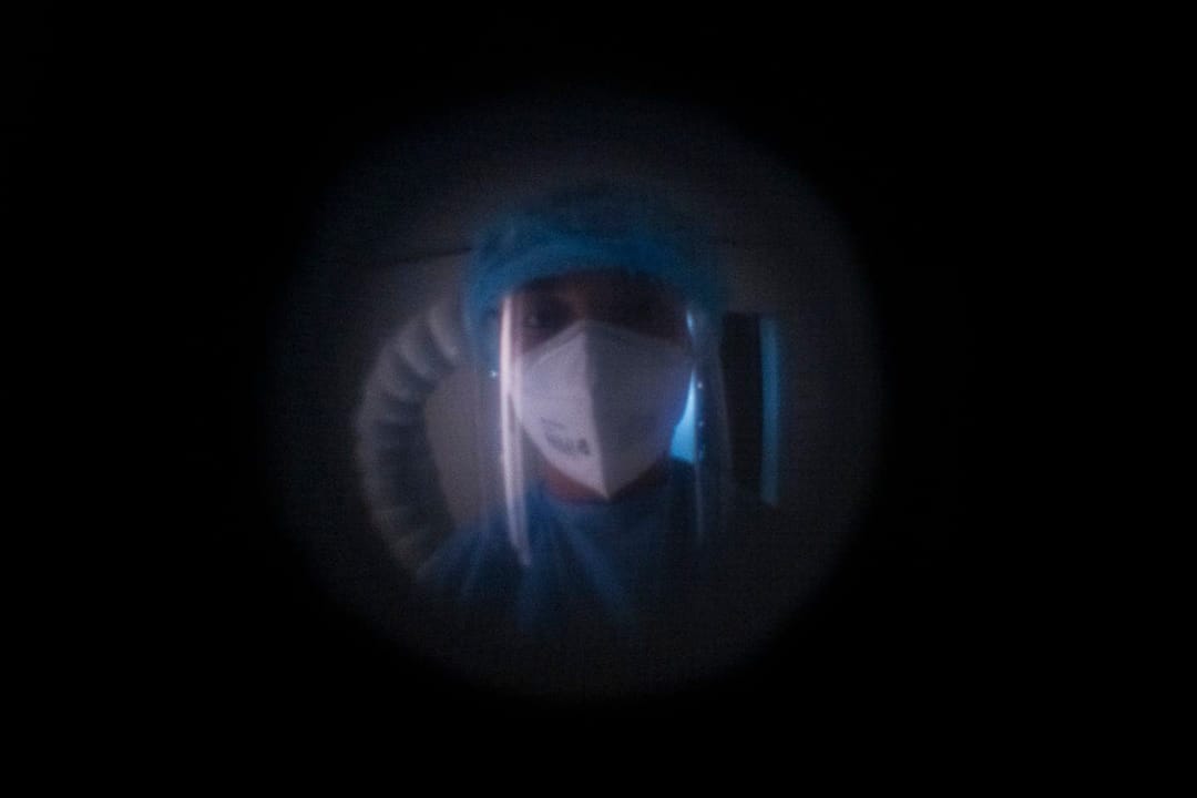 2022年5月9日，一名身穿 PPE 的酒店工作人員在政府指定的檢疫酒店的房間外等候，對一名接受檢疫命令的旅客進行核酸測試。