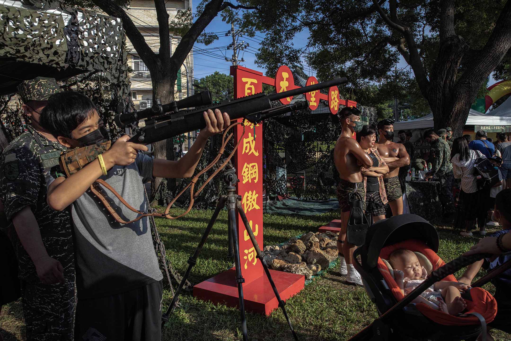 2022年9月17日，为强化全民国防，国防部在桃园马祖文创园区举办“进击的迷彩”活动，市民拿著枪观看。摄：陈焯𪸩/端传媒