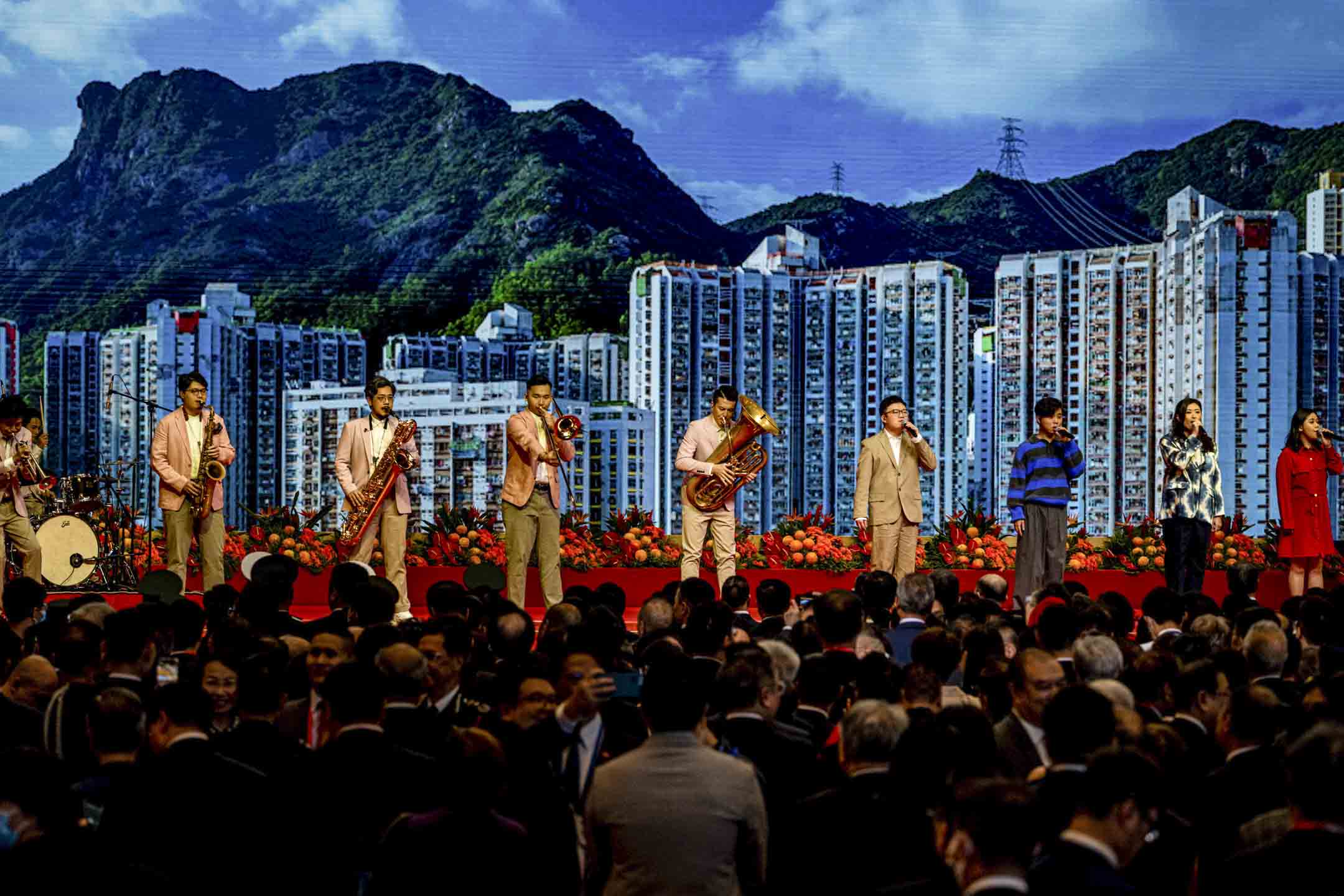 2023年7月1日,湾仔会展举办庆回归酒会,有音乐团体在台上演唱,后面背景为狮子山。摄:Ryan Lai/端传媒